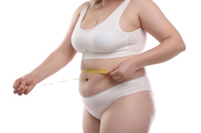Photo of Weight loss. Plus size woman measuring waist with tape on white background, closeup