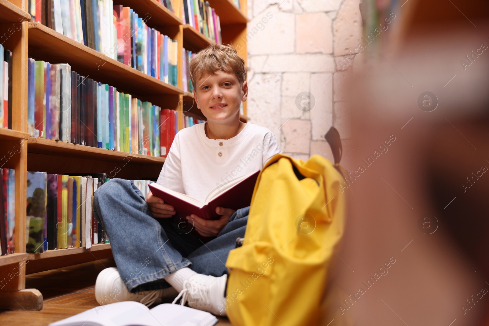 Student reading book on floor in library Photo of Student reading book on floor in library