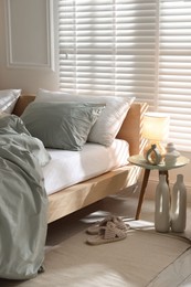 Photo of Comfortable bed with soft linens, lamp and decor in stylish room. Home textile