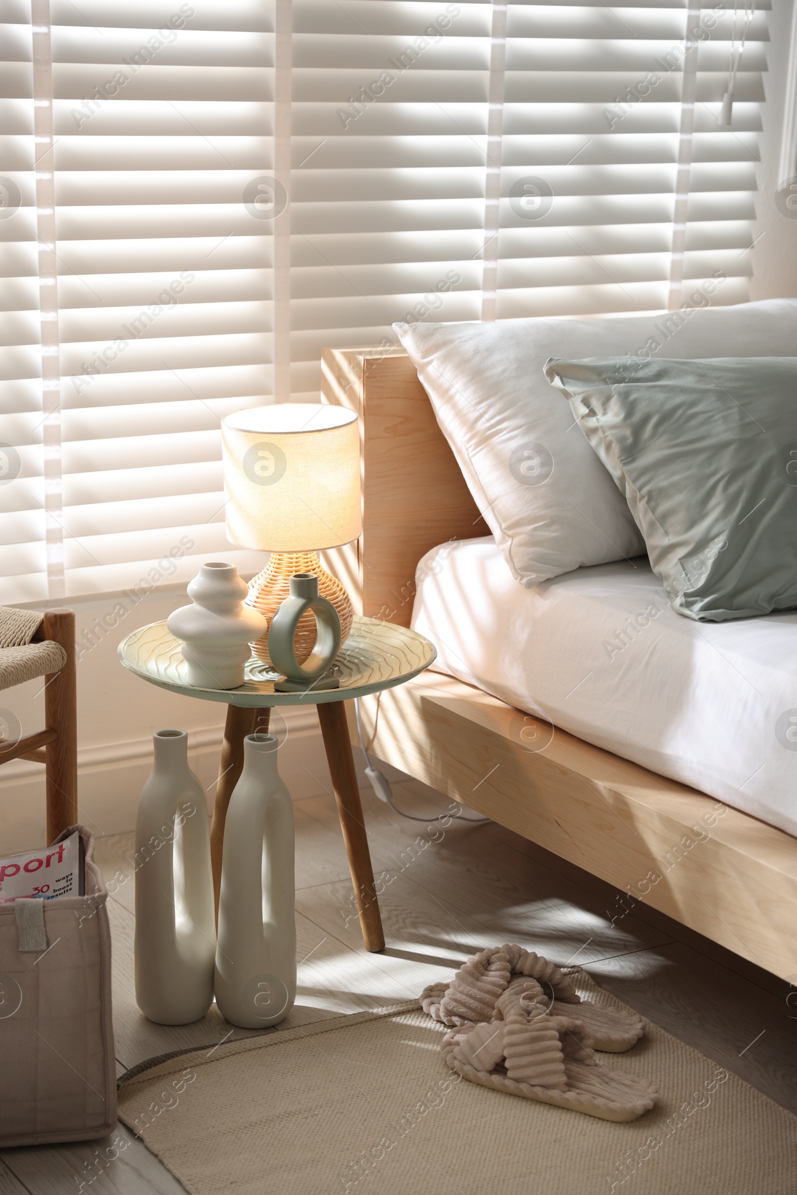 Comfortable bed with soft linens, lamp and decor in stylish room. Home textile Photo of Comfortable bed with soft linens, lamp and decor in stylish room. Home textile