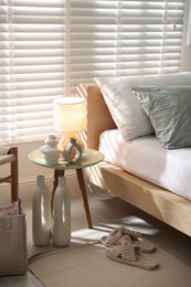 Photo of Comfortable bed with soft linens, lamp and decor in stylish room. Home textile