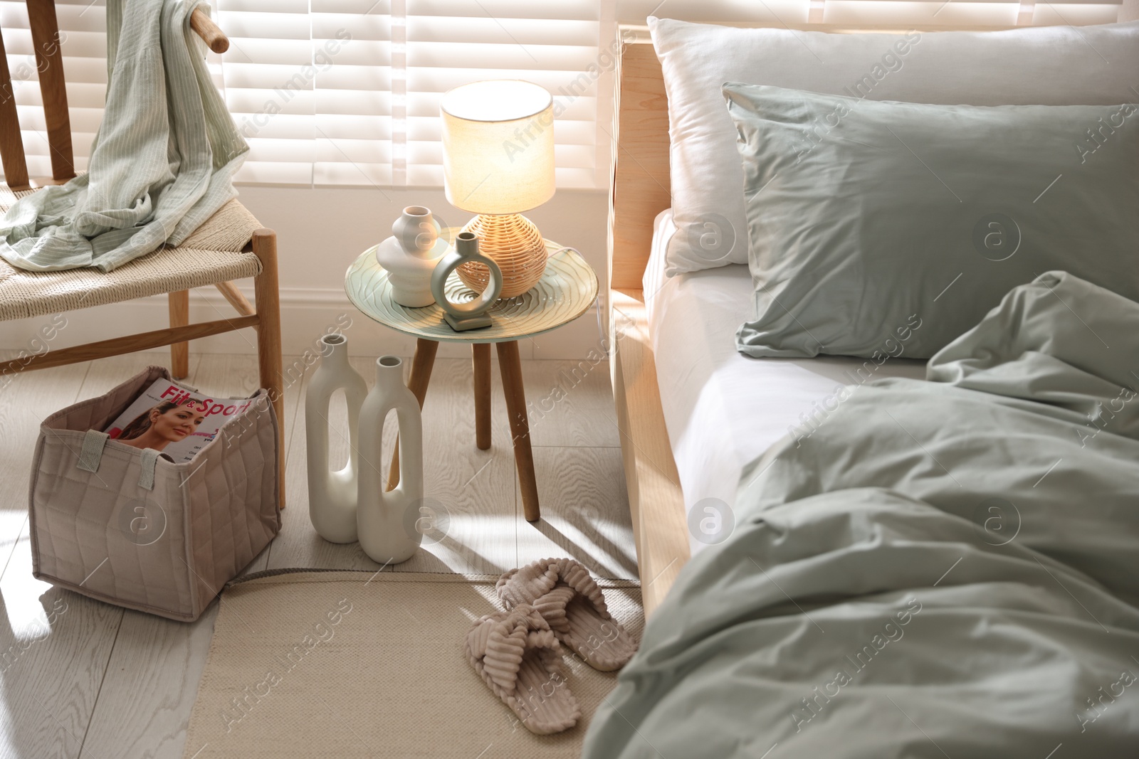 Comfortable bed with soft linens, lamp and decor in stylish room. Home textile Photo of Comfortable bed with soft linens, lamp and decor in stylish room. Home textile