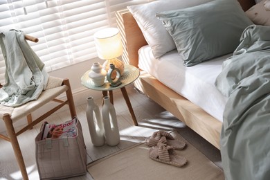 Photo of Comfortable bed with soft linens, lamp and decor in stylish room. Home textile