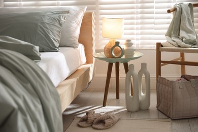 Photo of Comfortable bed with soft linens, lamp and decor in stylish room. Home textile