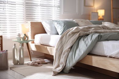 Photo of Comfortable bed with soft linens, lamp and decor in stylish room. Home textile