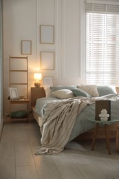 Photo of Comfortable bed with soft linens, lamp and decor in stylish room. Home textile