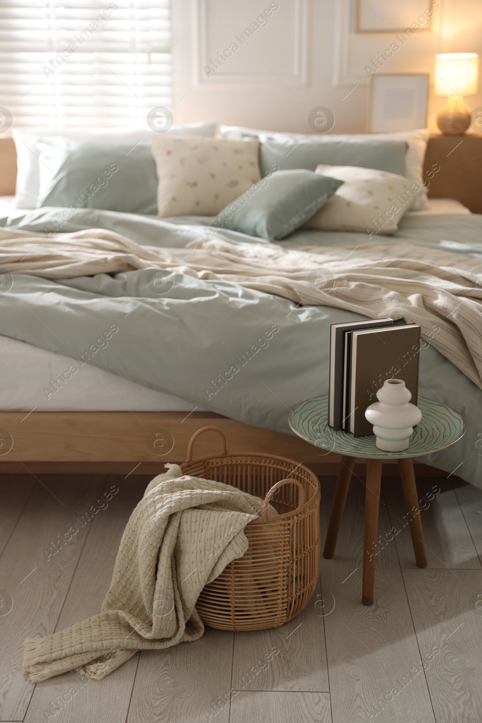 Comfortable bed with soft linens, lamp and decor in stylish room. Home textile Photo of Comfortable bed with soft linens, lamp and decor in stylish room. Home textile