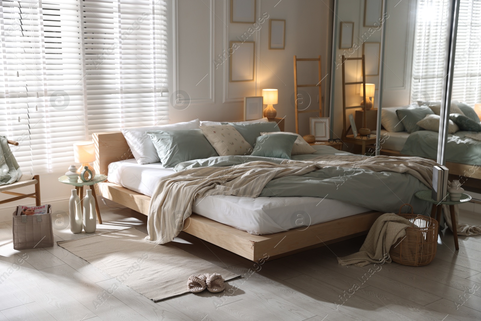 Photo of Comfortable bed with soft linens, lamp and decor in stylish room. Home textile
