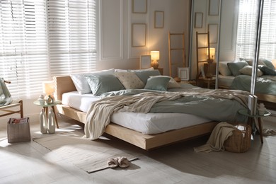Photo of Comfortable bed with soft linens, lamp and decor in stylish room. Home textile
