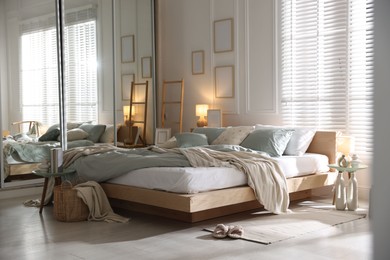 Photo of Comfortable bed with soft linens, lamp and decor in stylish room. Home textile