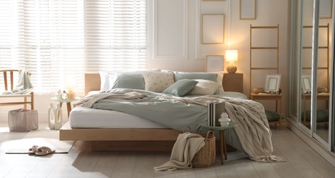 Photo of Comfortable bed with soft linens, lamp and decor in stylish room. Home textile