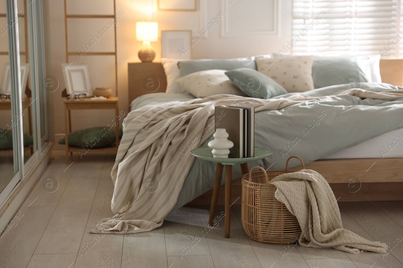Comfortable bed with soft linens, lamp and decor in stylish room. Home textile Photo of Comfortable bed with soft linens, lamp and decor in stylish room. Home textile