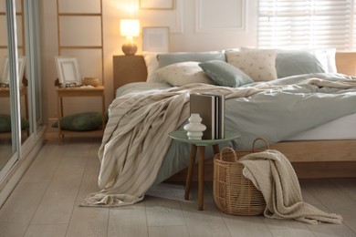 Photo of Comfortable bed with soft linens, lamp and decor in stylish room. Home textile