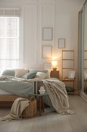 Photo of Comfortable bed with soft linens, lamp and decor in stylish room. Home textile
