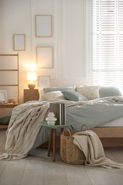 Photo of Comfortable bed with soft linens, lamp and decor in stylish room. Home textile