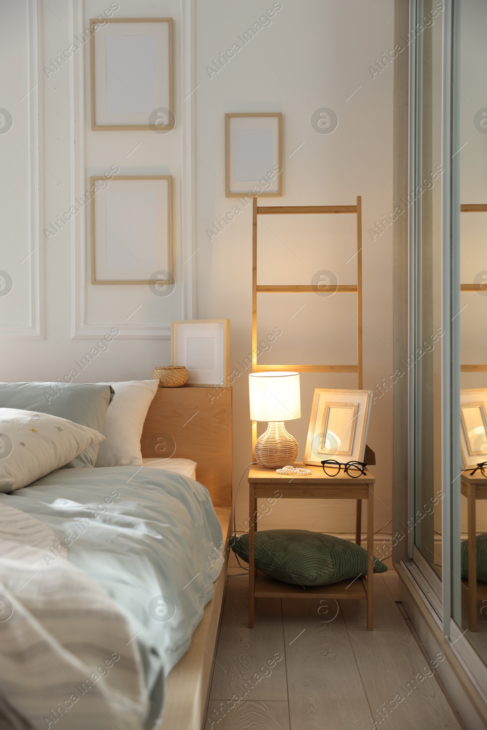 Photo of Comfortable bed with soft linens, lamp and decor in stylish room. Home textile
