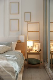 Photo of Comfortable bed with soft linens, lamp and decor in stylish room. Home textile