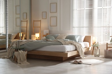 Photo of Comfortable bed with soft linens, lamp and decor in stylish room. Home textile