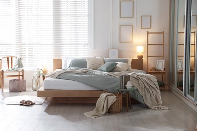 Photo of Comfortable bed with soft linens, lamp and decor in stylish room. Home textile