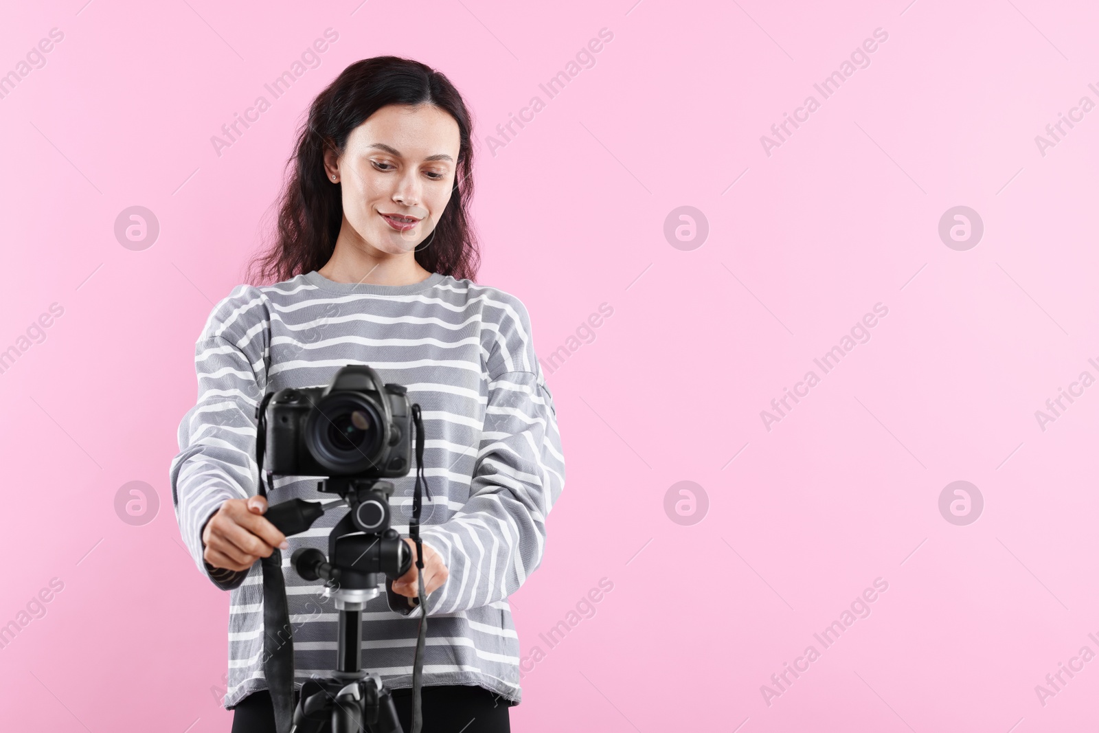 Woman with professional video camera on pink background, space for text Photo of Woman with professional video camera on pink background, space for text