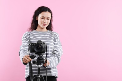 Photo of Woman with professional video camera on pink background, space for text