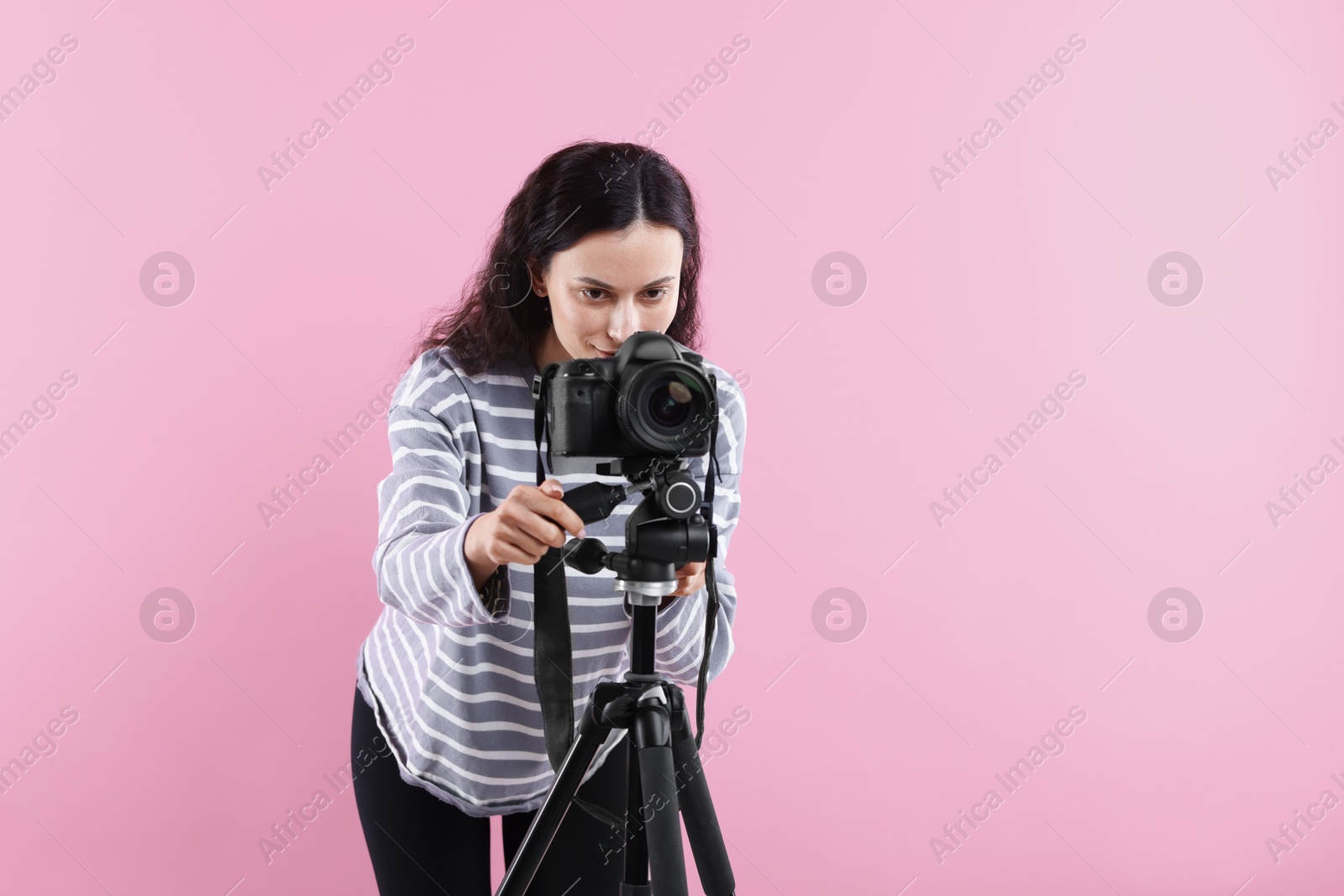 Woman with professional video camera on pink background, space for text Photo of Woman with professional video camera on pink background, space for text