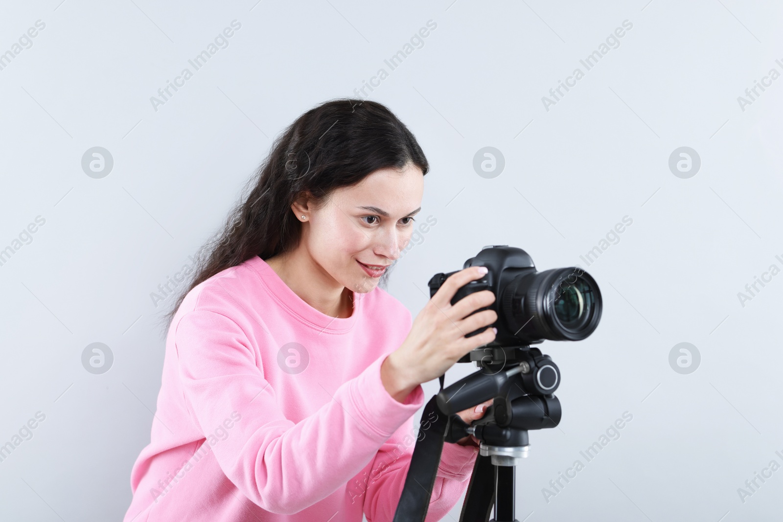 Woman with professional video camera on light grey background Photo of Woman with professional video camera on light grey background