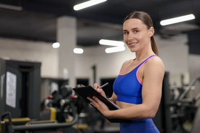 Photo of Professional personal trainer with clipboard in gym. Space for text