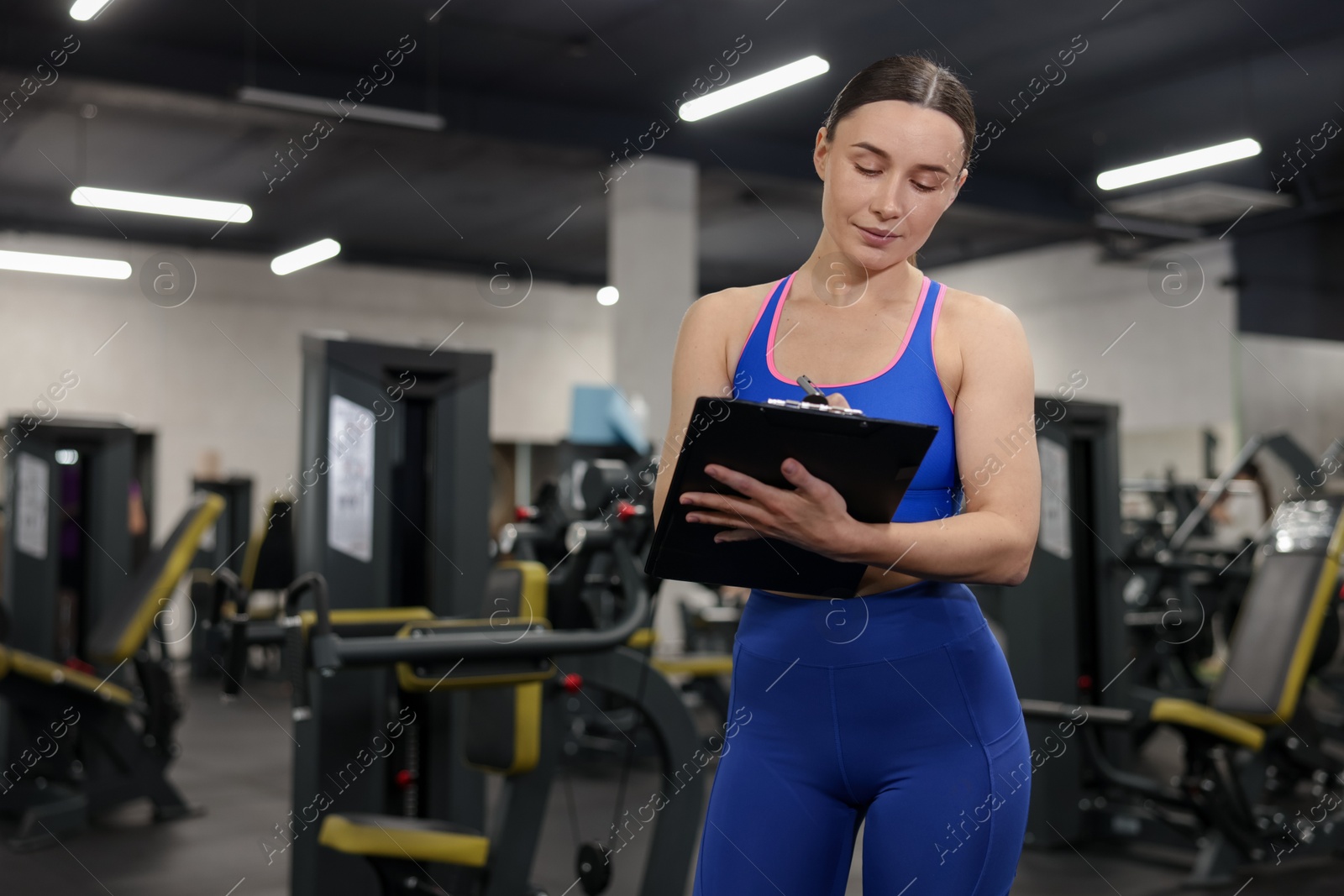 Professional personal trainer with clipboard in gym. Space for text Photo of Professional personal trainer with clipboard in gym. Space for text
