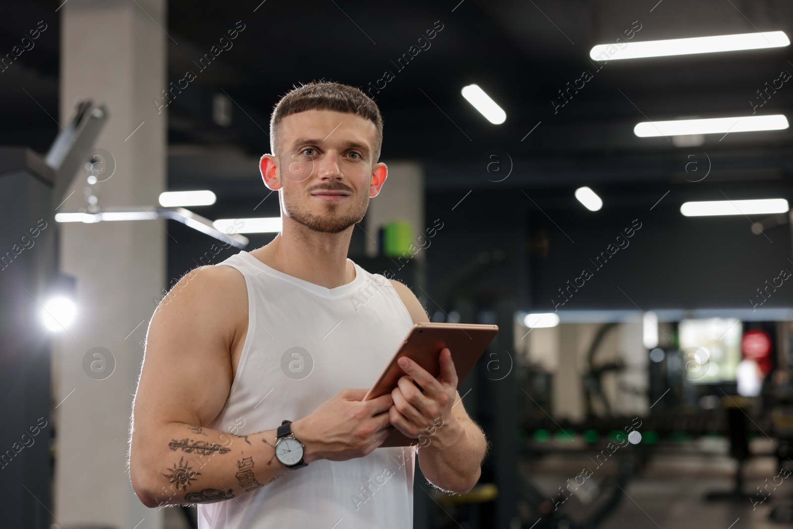 Photo of Personal trainer with tablet in sport center. Space for text