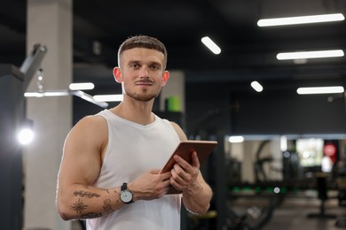 Photo of Personal trainer with tablet in sport center. Space for text