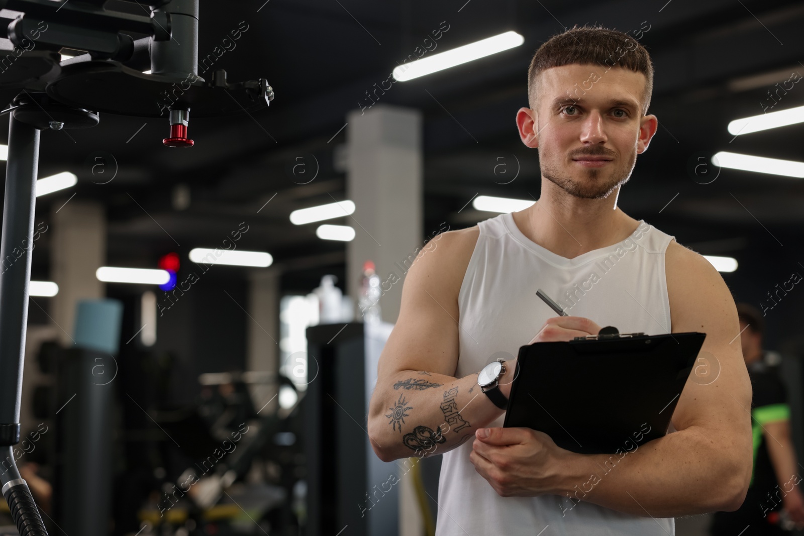 Personal trainer with clipboard in sport center. Space for text Photo of Personal trainer with clipboard in sport center. Space for text