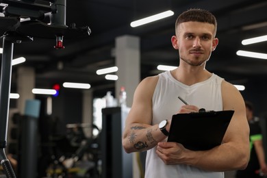Photo of Personal trainer with clipboard in sport center. Space for text