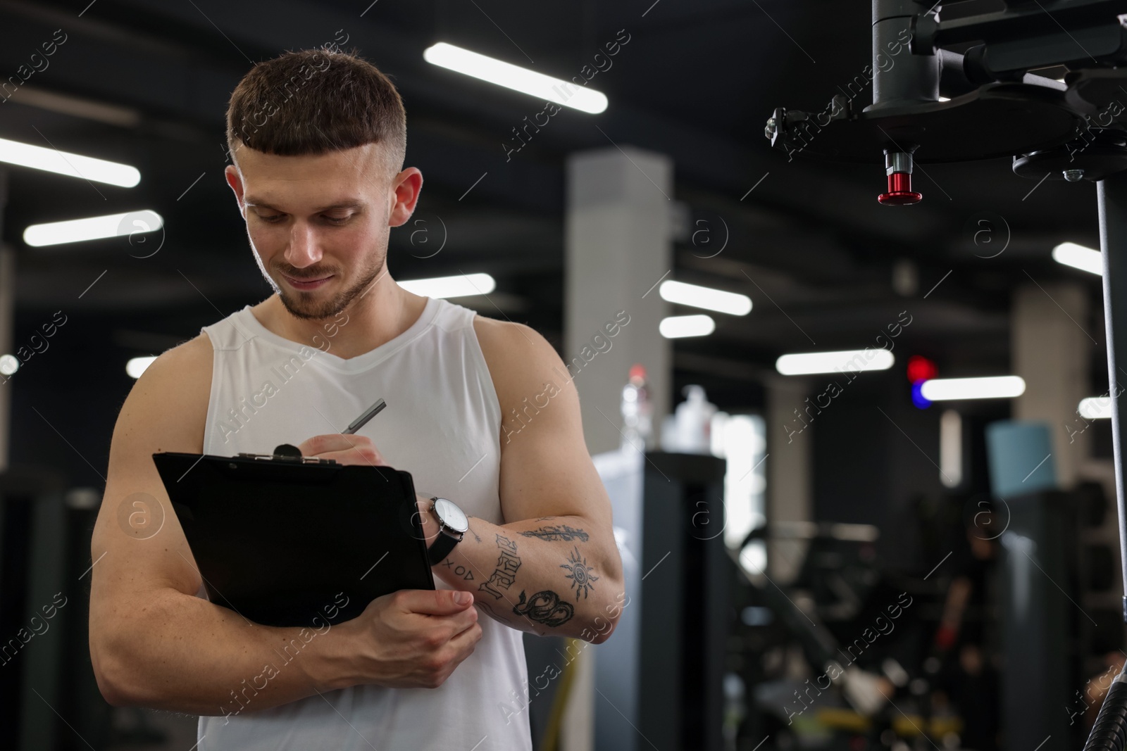 Personal trainer with clipboard in sport center. Space for text Photo of Personal trainer with clipboard in sport center. Space for text
