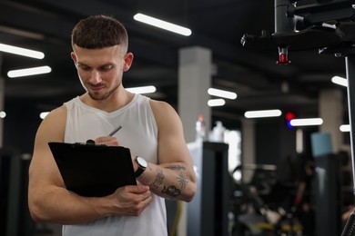 Photo of Personal trainer with clipboard in sport center. Space for text