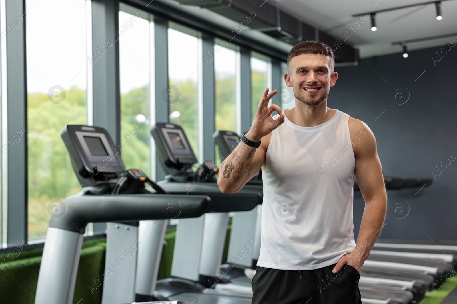 Personal trainer showing OK gesture in sport center. Space for text Photo of Personal trainer showing OK gesture in sport center. Space for text