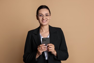 Photo of Confident business woman in suit with smartphone on beige background