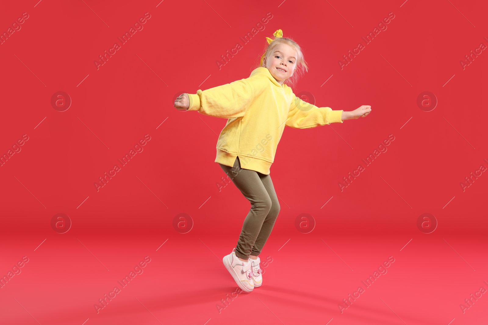 Cute little girl dancing on red background Photo of Cute little girl dancing on red background