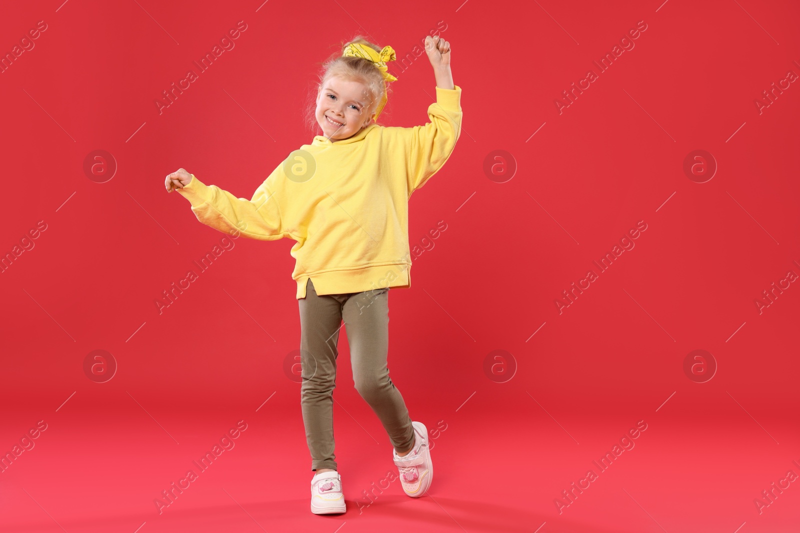 Cute little girl dancing on red background Photo of Cute little girl dancing on red background