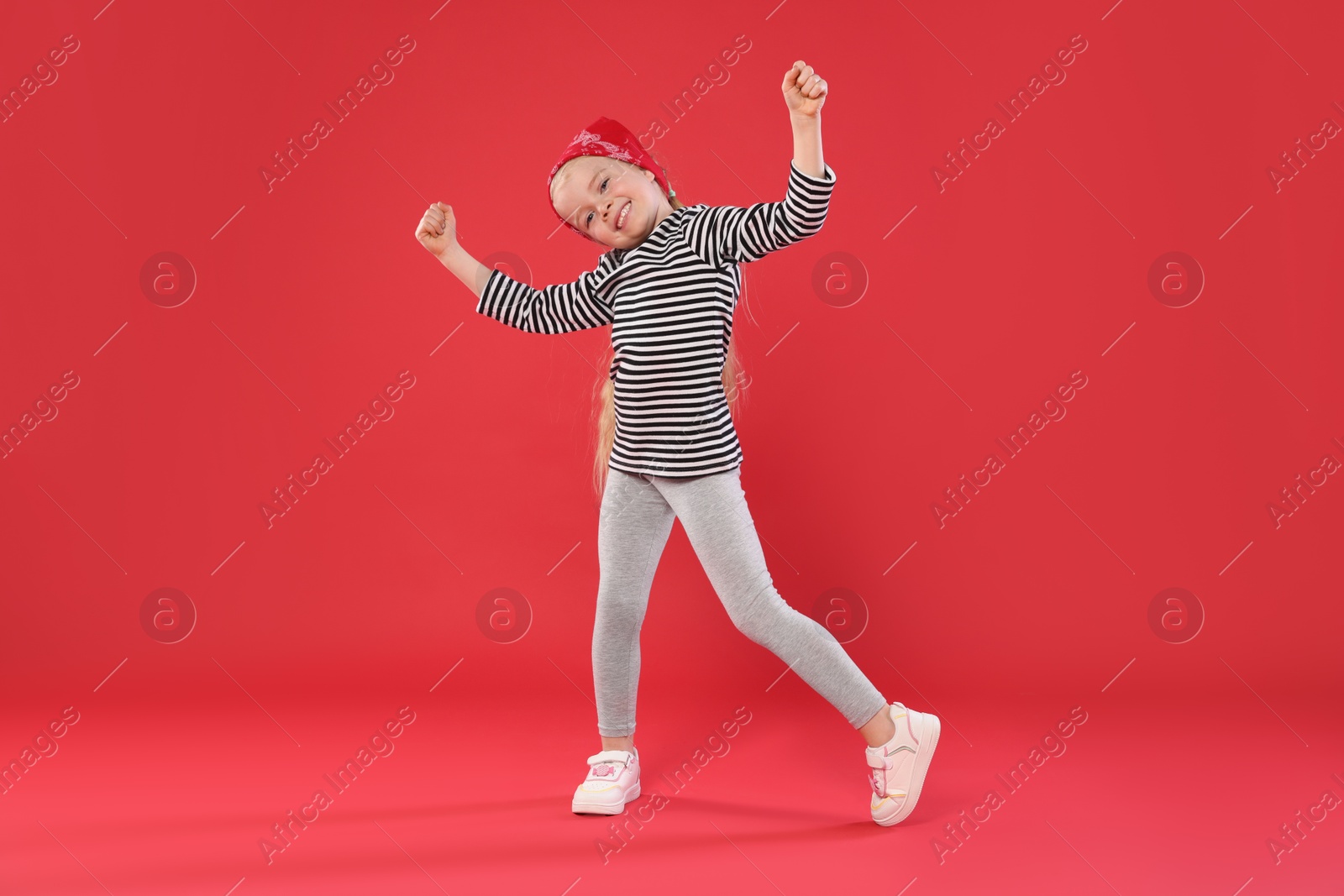 Cute little girl dancing on red background Photo of Cute little girl dancing on red background