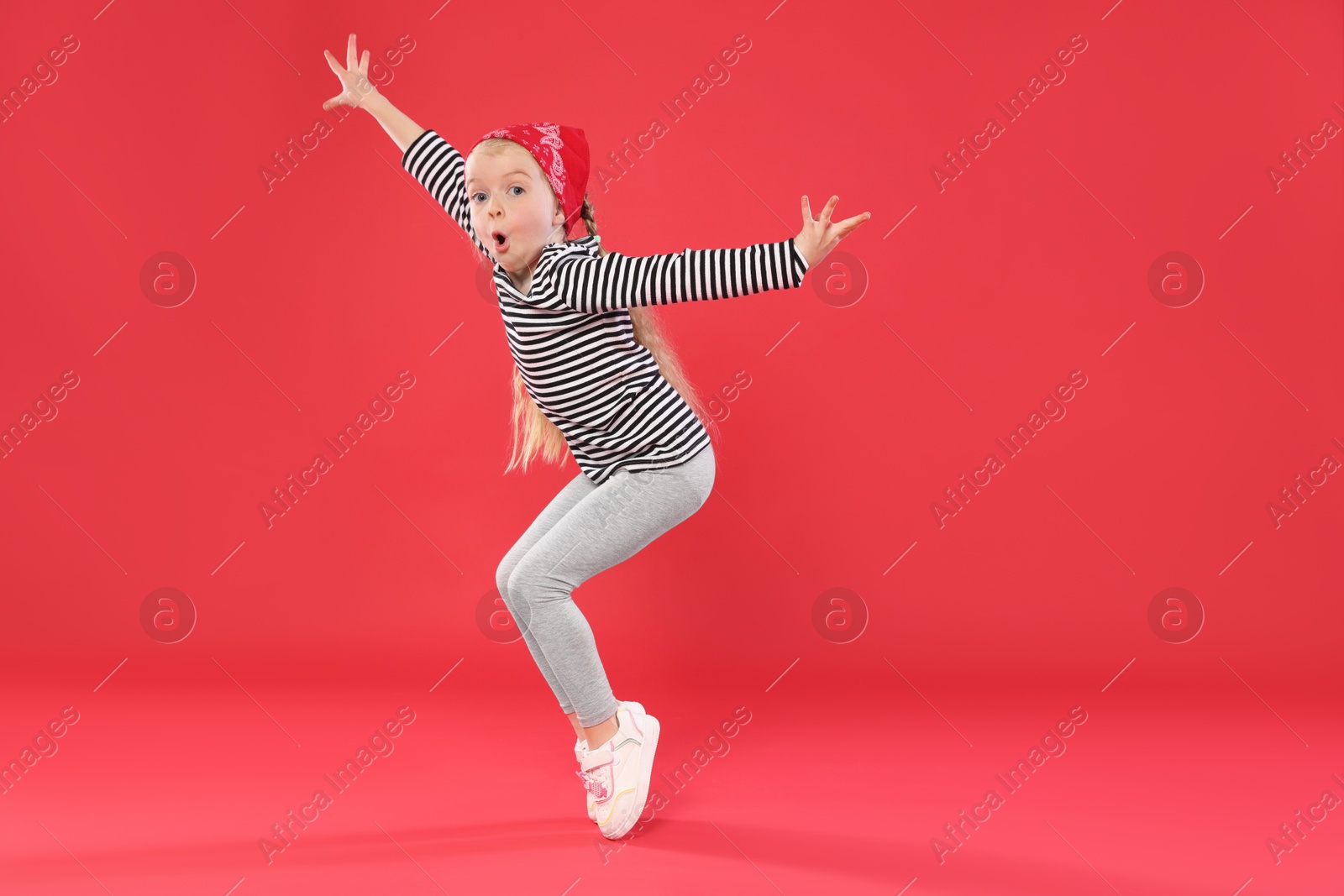 Cute little girl dancing on red background, space for text Photo of Cute little girl dancing on red background, space for text