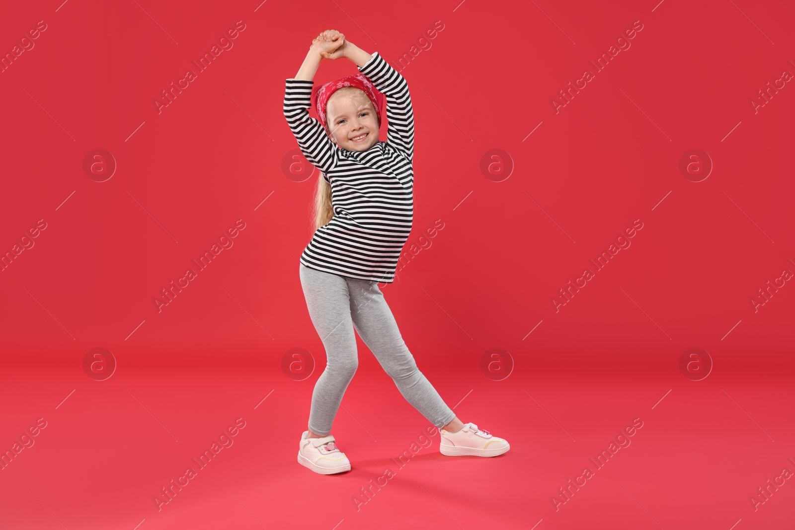 Cute little girl dancing on red background Photo of Cute little girl dancing on red background