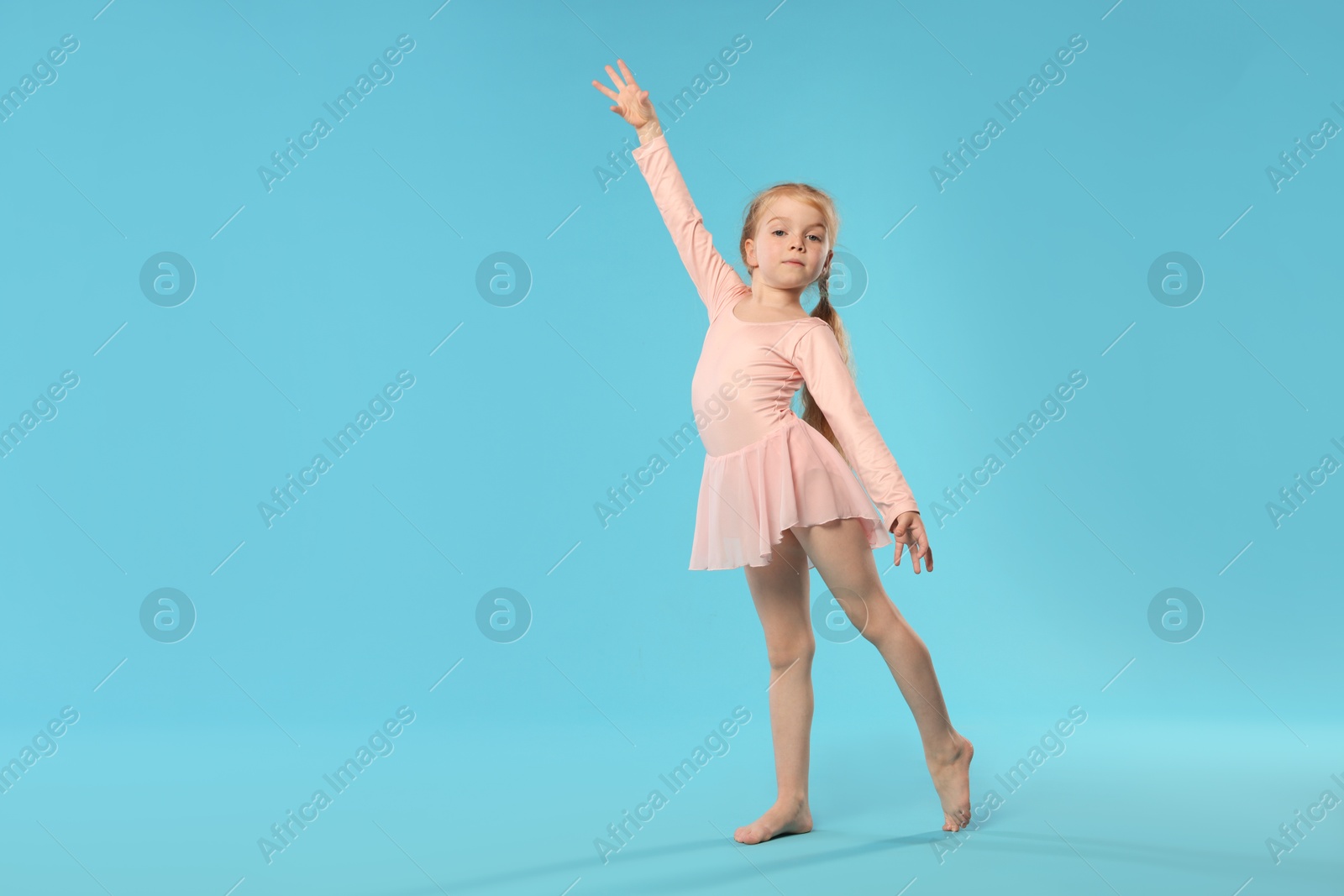 Cute little girl dancing on light blue background, space for text Photo of Cute little girl dancing on light blue background, space for text