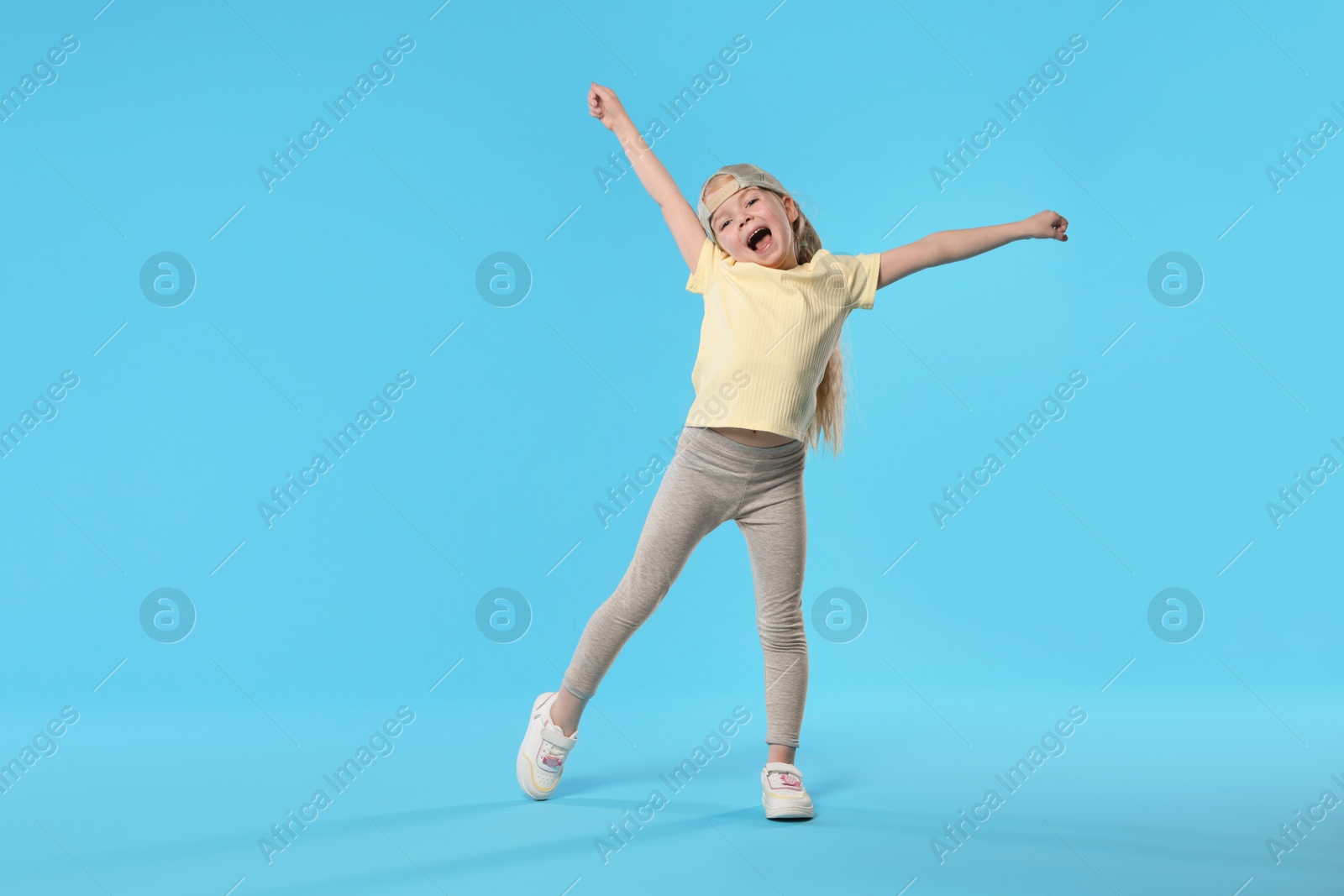 Cute little girl dancing on light blue background, space for text Photo of Cute little girl dancing on light blue background, space for text