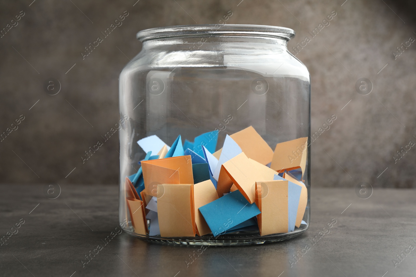 Jar with colorful pieces of paper on grey table, closeup Photo of Jar with colorful pieces of paper on grey table, closeup