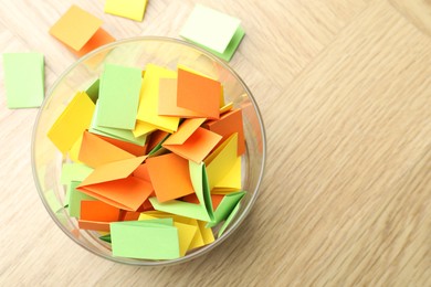 Photo of Jar with colorful pieces of paper on wooden table, top view. Space for text