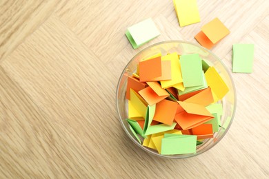 Photo of Jar with colorful pieces of paper on wooden table, top view. Space for text