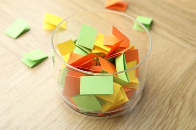 Photo of Jar with colorful pieces of paper on wooden table, closeup