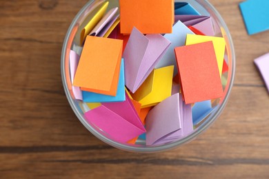 Photo of Jar with colorful pieces of paper on wooden table, top view