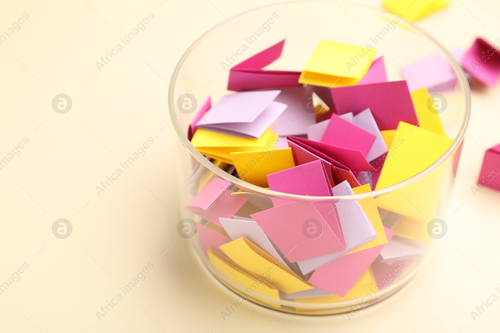 Photo of Jar with colorful pieces of paper on beige background, closeup